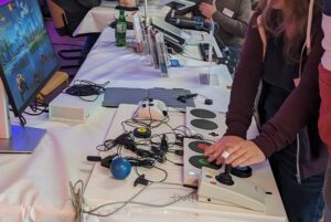 Tisch mit Kabeln, einem Bildschirm, Joystick und weiteren assistiven Technologien, die von einer Person benutzt werden